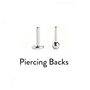 Op de afbeelding: Twee zilverkleurige metalen piercingonderdelen worden getoond. Het ene onderdeel heeft een platte ronde basis met een verticale staaf, terwijl het andere bestaat uit een kleine bolvormige bal bevestigd aan een verticale staaf. De tekst Piercing Backs is zichtbaar.