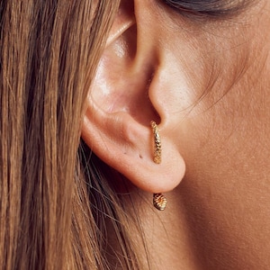 Female model wearing snake ear jacket earrings in 24K gold-plated finish for a chic look.