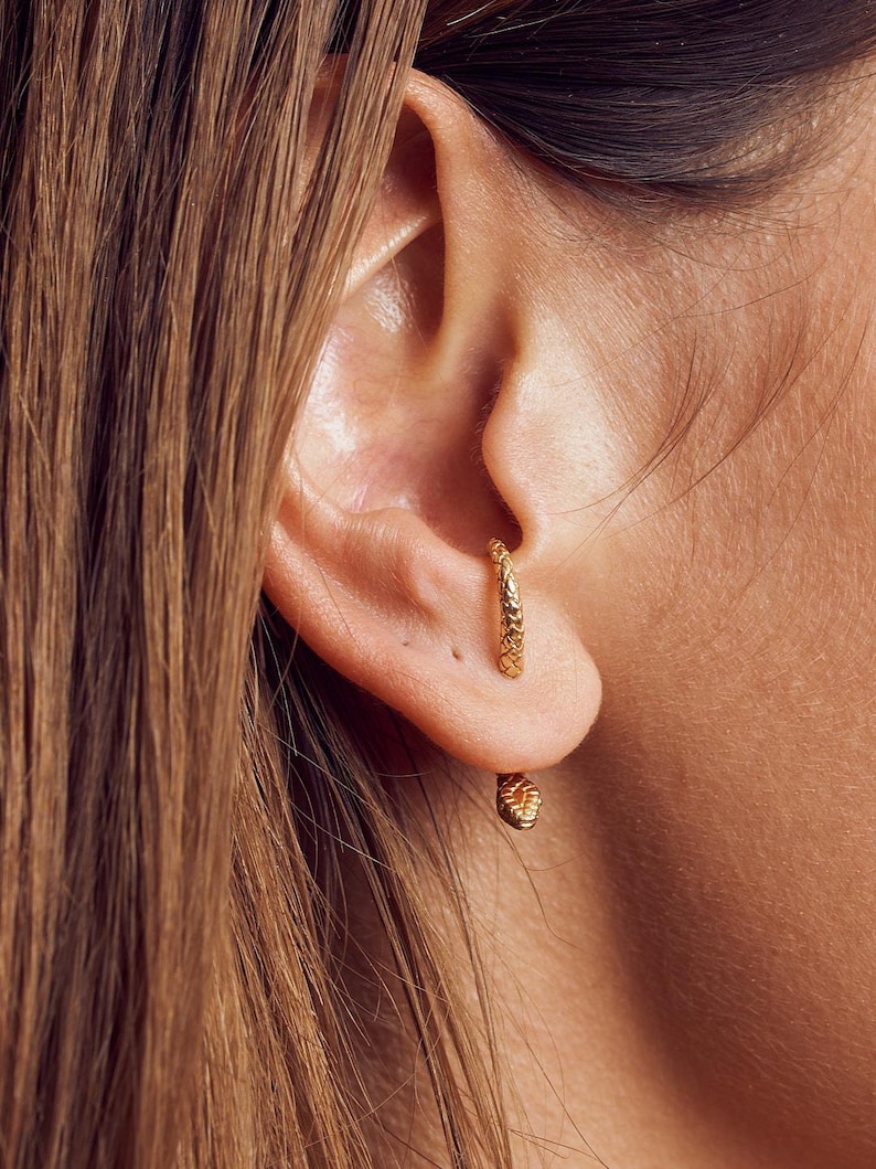 Female model wearing snake ear jacket earrings in 24K gold-plated finish for a chic look.