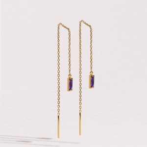 May include: A pair of gold chain earrings with purple gemstone accents. The earrings are long and dangle from the earlobe.