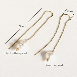 May include: Two pairs of gold chain earrings with pearl accents. One pair features a flat button pearl and the other features a baroque pearl. The chains are 70 mm long and the pearl accents are 10 mm in diameter.
