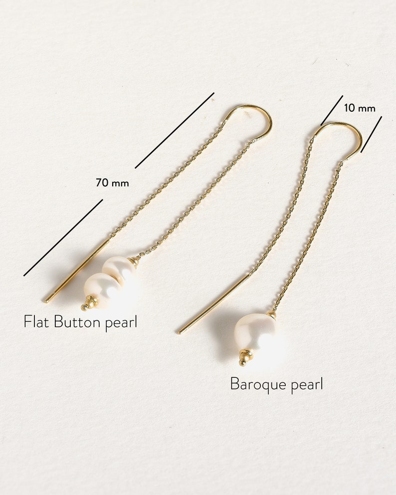 May include: Two pairs of gold chain earrings with pearl accents. One pair features a flat button pearl and the other features a baroque pearl. The chains are 70 mm long and the pearl accents are 10 mm in diameter.