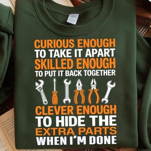 May include: Dark green sweatshirt with the text "CURIOUS ENOUGH TO TAKE IT APART SKILLED ENOUGH TO PUT IT BACK TOGETHER CLEVER ENOUGH TO HIDE THE EXTRA PARTS WHEN I'M DONE". The design includes illustrations of tools.
