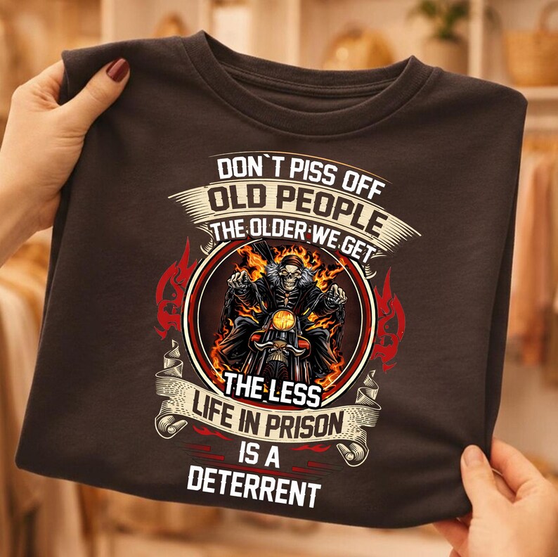 a person holding a black t-shirt with a graphic design and text on it.