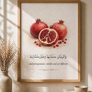 Könnte beinhalten: Gerahmter Kunstdruck mit drei Granatäpfeln, einer davon aufgeschnitten, um die Kerne zu zeigen. Der Druck enthält arabischen Text und den englischen Satz „and pomegranates, similar and yet different“. Der Rahmen ist hellbraun.