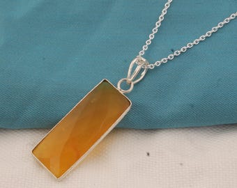 May include: A silver necklace with a rectangular pendant featuring a faceted, amber-colored gemstone. The pendant is set in a silver bezel and hangs from a delicate silver chain. The gemstone has a gradient of colors, ranging from yellow to orange.