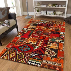 Peut inclure: Un tapis rectangulaire avec un motif patchwork. Le tapis présente un mélange de couleurs vives, notamment du rouge, de l'orange et du sarcelle, avec des motifs géométriques et tribaux. Le tapis est posé sur un parquet.