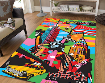 Op de afbeelding: Een kleurrijk vloerkleed met een New York City thema. Het toont iconische bezienswaardigheden zoals het Vrijheidsbeeld, het Empire State Building en een gele taxi. Het ontwerp gebruikt levendige kleuren en de woorden "New Yorker" en "Broadway".