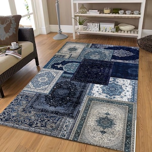 May include: A rectangular area rug with a patchwork design. The rug features various rectangular and square patterns in shades of blue, from light to dark. Each patch has a different ornate, floral-inspired design. The rug is placed on a wooden floor.