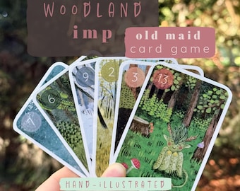 Könnte beinhalten: Ein Fächer aus Woodland Imp Old Maid Spielkarten mit handgezeichneten Waldszenen und nummerierten runden Symbolen. Die Karten zeigen fantasievolle Kreaturen, Bäume und Pilze in Grün-, Braun- und Blautönen mit weißen Rändern.