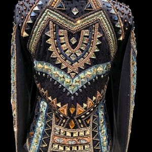 K&ouml;nnte beinhalten: Eine schwarze Langarmjacke mit einer komplexen Anordnung aus geometrischen Kristallen, Metallnieten und Perlen in Gold-, Bronze- und Hellblaut&ouml;nen, die ein symmetrisches Muster auf dem R&uuml;cken und den &Auml;rmeln bilden.
