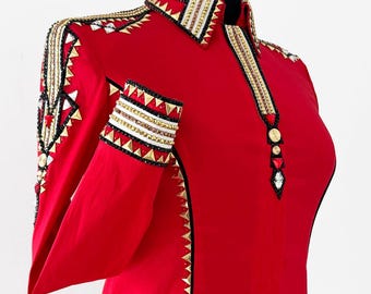 May include: A vibrant red equestrian show jacket with gold, black, and white embellishments. The jacket features a high collar, long sleeves, and decorative trim along the seams and shoulders. The design includes geometric patterns and sparkling accents.