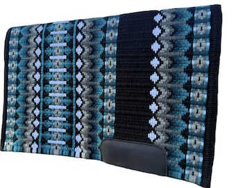 May include: A rectangular horse saddle pad with a black spine and a black leather patch. The pad features a geometric pattern in shades of teal, gray, and white. The edges are black.