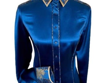 May include: A long-sleeved, royal blue satin shirt with a button-up front. The collar and cuffs feature a patterned design with gold and navy accents. The shirt is displayed on a mannequin.