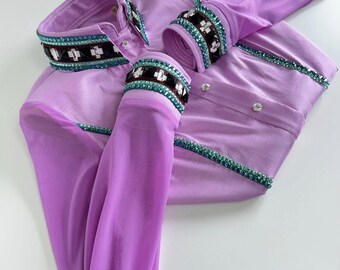 May include: A lavender-colored shirt with long sleeves. The collar and cuffs are adorned with a decorative band featuring white crosses and teal accents. The shirt has a button-down front and is made of a silky material.