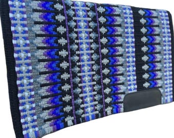 May include: A rectangular saddle pad with a woven pattern in shades of blue, gray, and black. The design features geometric shapes and vertical stripes. The pad has a black border and a black leather patch on the bottom right corner.
