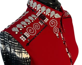 May include: A red show shirt with intricate embellishments. The collar and shoulders feature white, black, and silver decorative elements. The sleeves have a black and white patterned design.