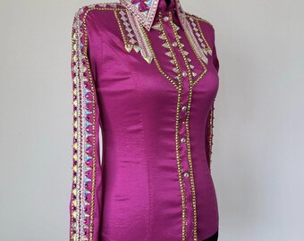 May include: A magenta-colored, long-sleeved shirt with a collared neckline. The shirt is adorned with gold and iridescent embellishments along the collar, cuffs, and front. The shirt is displayed on a black mannequin.