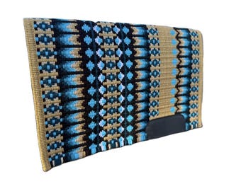 May include: A rectangular saddle pad featuring a woven pattern in shades of tan, black, and light blue. The design consists of vertical stripes and geometric shapes. A solid black leather-like patch is positioned on the lower right corner.