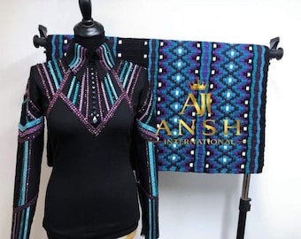 May include: A black long-sleeve shirt with a pointed collar and a front button placket, decorated with vertical rows of teal and purple crystals. Behind the shirt hangs a matching black, teal, and purple patterned saddle pad with the text AJI ANSH INTERNATIONAL.