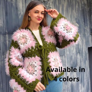 Peut inclure: Un cardigan à manches longues en fil vert olive avec des carrés composés de laine rose et blanche à texture duveteuse. Le vêtement présente une fermeture à nouer sur le devant et est fait de carrés granny au crochet. Texte : Available in 4 colors.