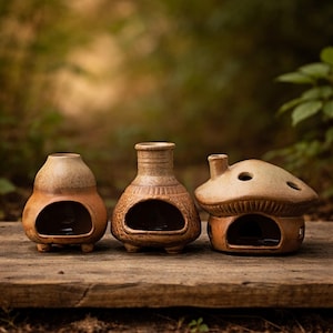 May include: Three ceramic candle holders in a row, each with a unique design. The candle holders are brown and tan, with a rustic finish. The first is gourd-shaped, the second is vase-shaped, and the third is a mushroom house.