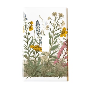 May include: A white light switch cover featuring a botanical illustration of wildflowers. The design includes yellow, blue, and pink flowers with green foliage. The switch plate is rectangular with a single switch opening.