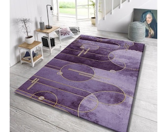 May include: A rectangular area rug with a purple and lavender color scheme. The rug features a geometric design with gold-colored circles and lines. The rug is placed on a light-colored wooden floor.