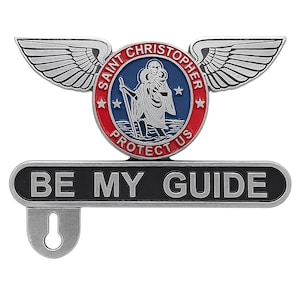 May include: A silver-toned Saint Christopher pendant with wings, a circular emblem, and the text "BE MY GUIDE." The emblem features a depiction of Saint Christopher and the words "PROTECT US."