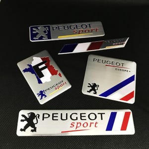Op de afbeelding: Vijf rechthoekige en schuine metalen emblemen met het Peugeot Sport-logo, de Franse vlag en het leeuwembleem. De ontwerpen bevatten geborstelde zilveren afwerkingen, blauwe, witte en rode kleuraccenten en tekst met Peugeot Sport of Peugeot Europe.