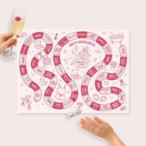 Op de afbeelding: Een roze en wit bordspel voor een vrijgezellenfeest, met rode tekst en illustraties. Het spelbord heeft een kronkelend pad met vakken met de tekst "Safe", "Drink" en "Swap". Dobbelstenen en een champagneglas zijn ook zichtbaar.