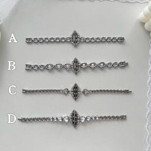 May include: Four silver-toned bracelets with different chain designs. Each bracelet features a central decorative element and a clasp. The bracelets are labeled A, B, C, and D. Bracelet B has pearl-like accents, and bracelet D has heart-shaped gems.