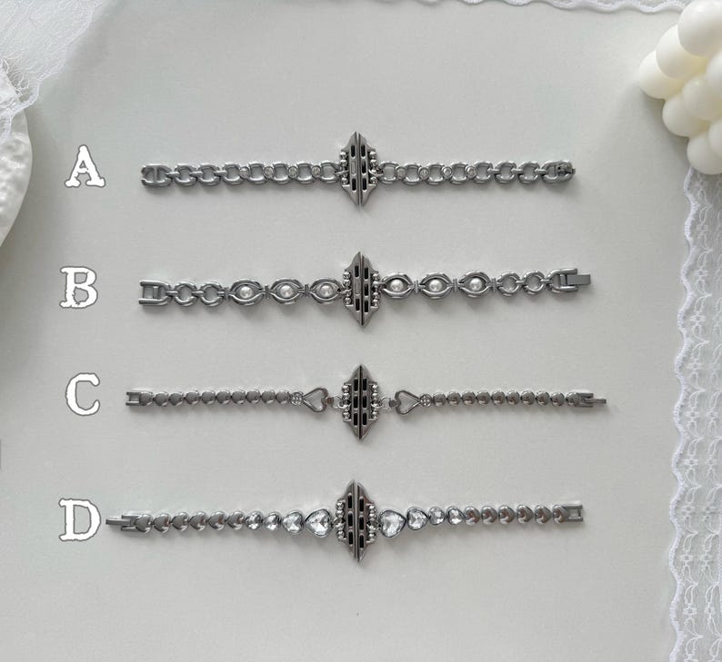 May include: Four silver-toned bracelets with different chain designs. Each bracelet features a central decorative element and a clasp. The bracelets are labeled A, B, C, and D. Bracelet B has pearl-like accents, and bracelet D has heart-shaped gems.