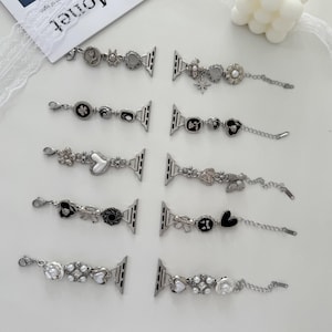 May include: A collection of decorative watch bands with various charms. The bands feature silver-toned metal with embellishments like flowers, hearts, pearls, and geometric shapes. Each band has a clasp for attachment to a smartwatch.