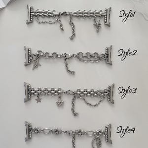 May include: Four silver watch straps with various chain and charm designs. Styles include chains, stars, and a religious pendant. Each strap is labelled with a style number. The straps are displayed on a white surface.