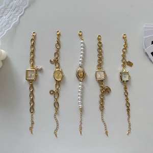 May include: Five gold-toned vintage-style bracelet watches with different face shapes and chain designs. One watch has a square face with a crystal accent, another has a pearl band, and the others have oval or square faces.