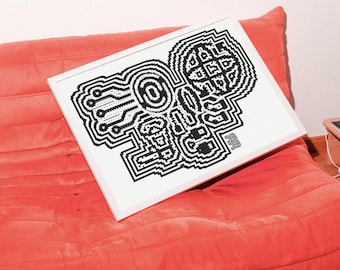 May include: A framed black and white pixel art print featuring an abstract design with geometric shapes and circuit board elements. The artwork is displayed on a white background within a white frame, resting on a coral-colored cushion.