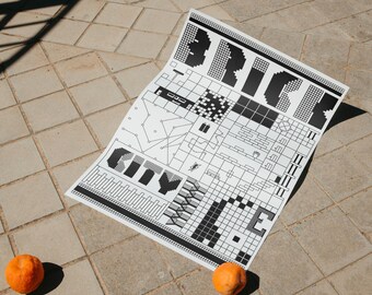 May include: A black and white graphic print titled "BRICK CITY WIDE" on a white sheet of paper. The print features geometric shapes and text. Two oranges are placed near the bottom of the paper on a tiled surface.