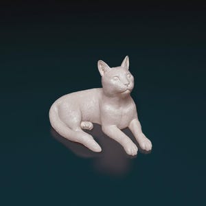 May include: A white cat figurine in a relaxed pose, with its front paws extended and head lifted. The sculpture has a smooth finish and is set against a dark teal background. This decorative cat statue is a charming home decor item.