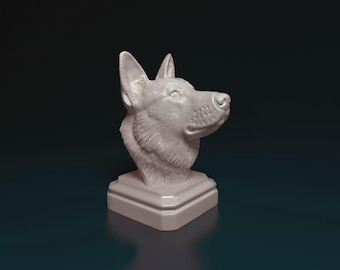 Puede incluir: Una escultura de color claro de la cabeza de un perro, colocada sobre una base cuadrada. La cabeza del perro está girada hacia un lado, con detalles de pelaje y rasgos faciales. La escultura es probablemente de yeso o un material similar.
