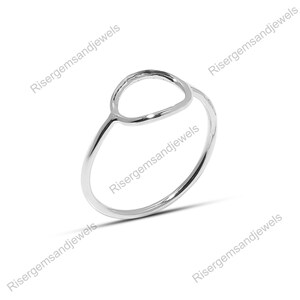 Op de afbeelding: Een zilveren ring met een minimalistisch design. De ring heeft een slanke band en een cirkelvormige open vorm aan de bovenkant. De ring is gemaakt van glanzend, reflecterend metaal.
