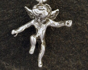 Puede incluir: Un collar de cadena de plata con un pequeño colgante de querubín de plata. El querubín está representado con alas y en una pose juguetona.