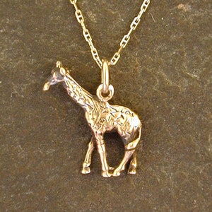 May include: A gold chain necklace with a detailed giraffe pendant.
