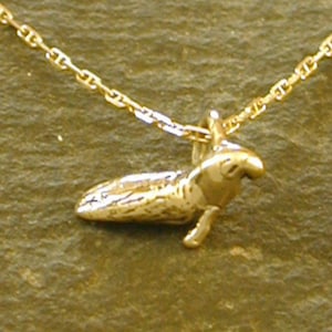 May include: A gold chain necklace with a small, detailed gold pendant shaped like a bird.