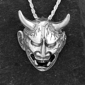 May include: A silver necklace with a detailed, three-dimensional pendant of a Japanese demon mask.