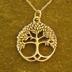 May include: A gold necklace with a tree of life pendant. The pendant is a detailed cutout of a tree with branches and leaves.