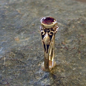 May include: A gold ring with an ornate design and a deep purple gemstone.