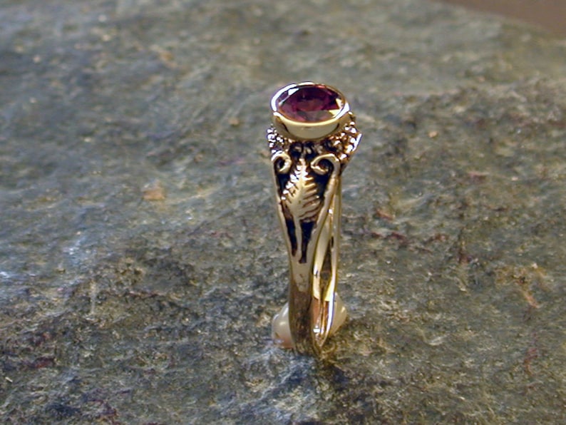 May include: A gold ring with an ornate design and a deep purple gemstone.