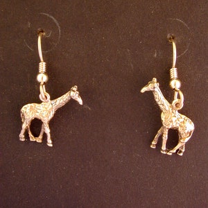 May include: A pair of gold-tone earrings featuring a detailed giraffe design. The earrings are dangle style with a hook closure.