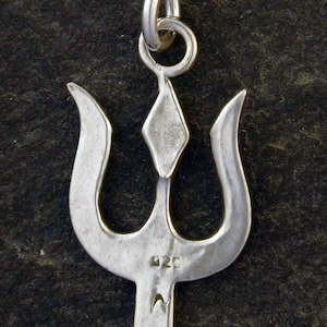 May include: Silver trident pendant with a diamond-shaped top and a loop for a chain. The back of the pendant has the markings "925" and "N".